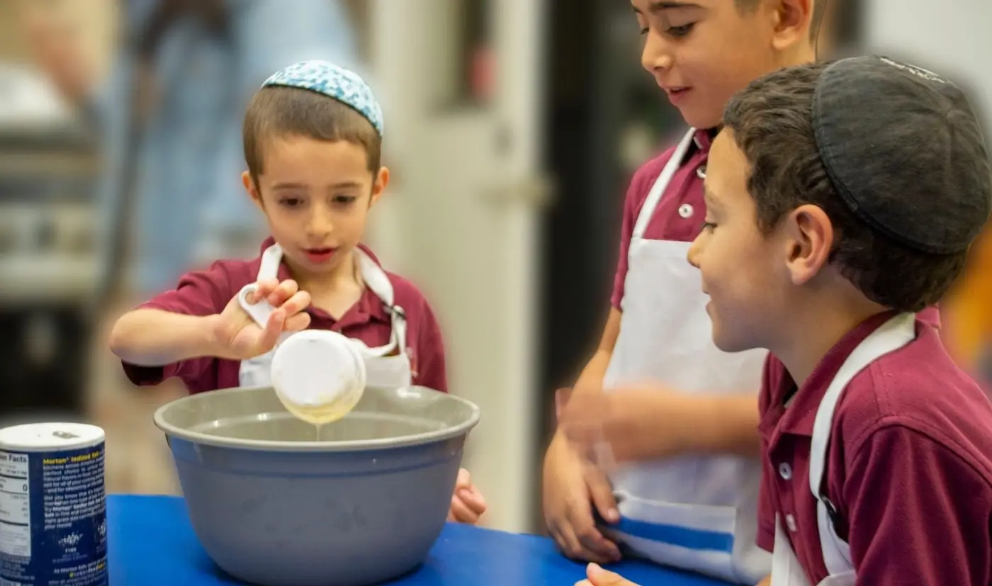 Students leaning in to see a Torah up close—wonder leading the way.
