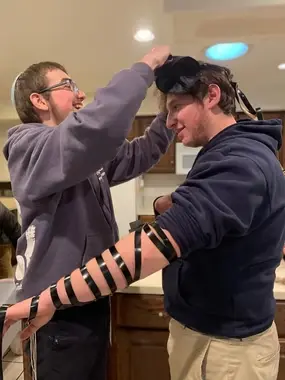 Two teens putting on tefillin