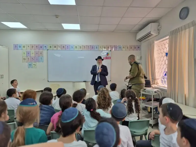 תלמידים יושבים בכיתה ומקשיבים למפגש, על הקיר אותיות האלף־בית