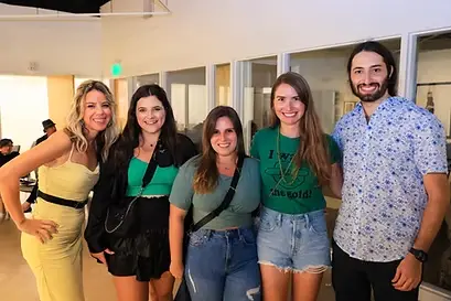 Five young professionals smiling together at a networking event.