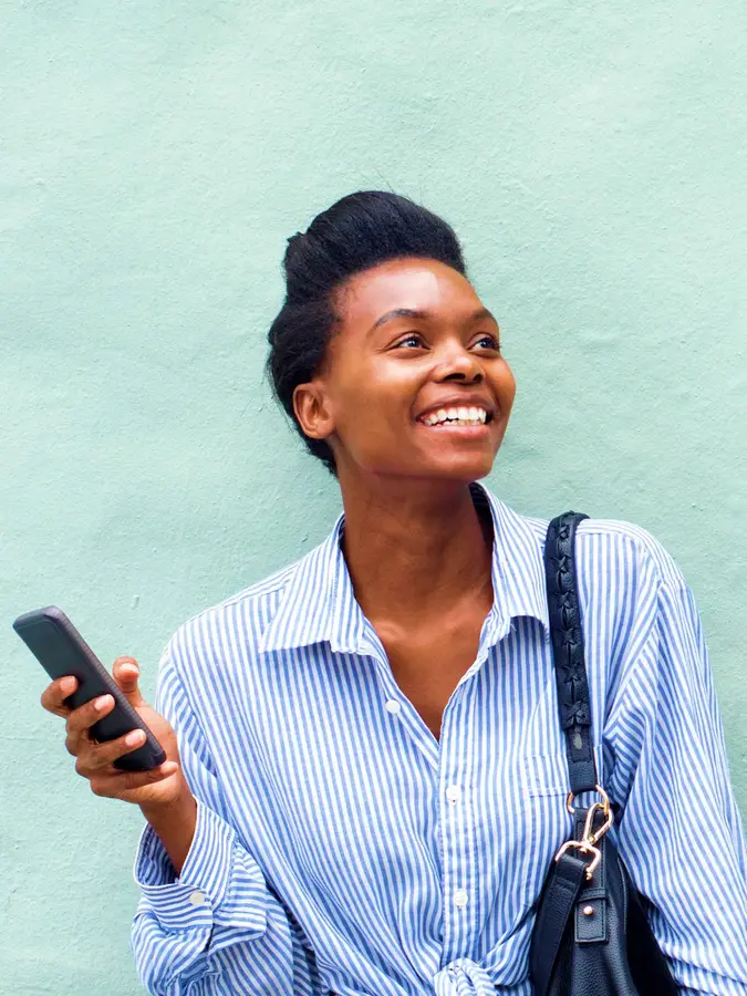 Femme debout dehors au soleil tenant son téléphone