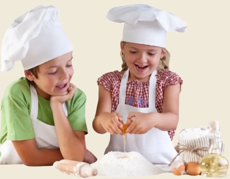 Two children wearing chef hats and aprons, cooking and baking together in a kitchen.